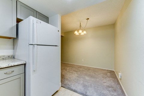 A white refrigerator stands in a kitchen next to a counter.