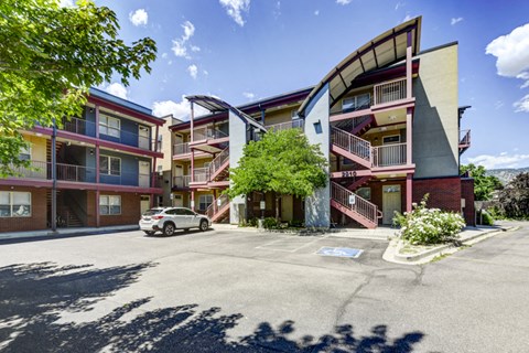 A parking lot in front of a multi-story apartment building.