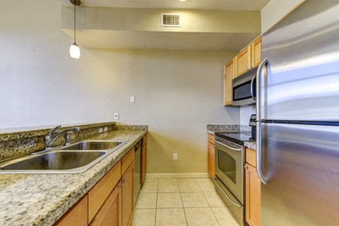 A kitchen with a granite counter top and stainless steel appliances.