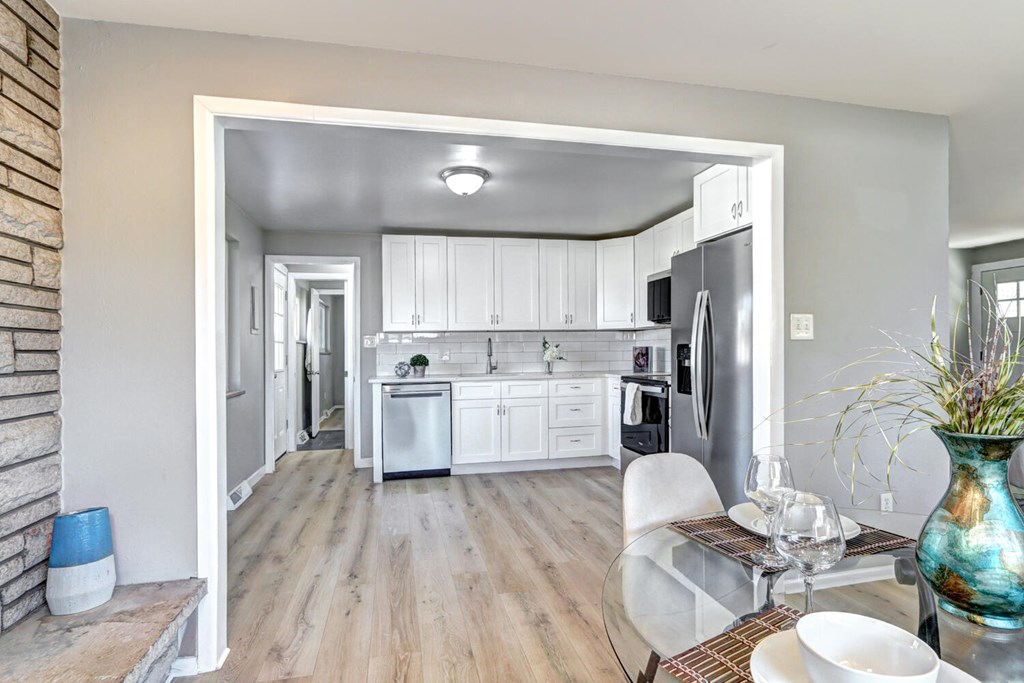A kitchen with white cabinets and a refrigerator.