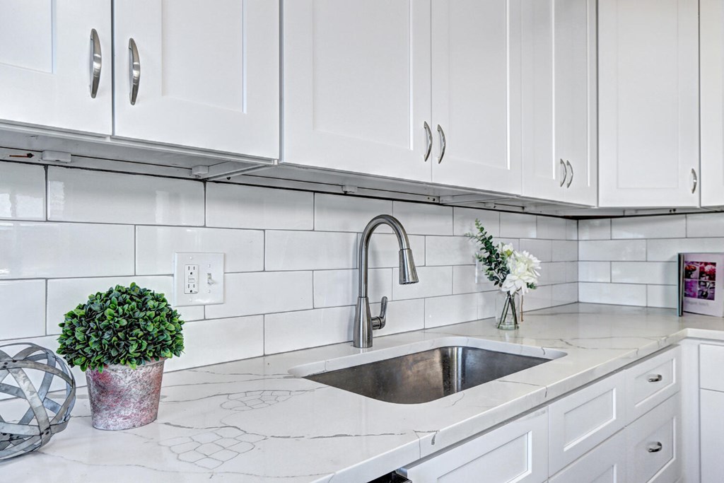 A kitchen with white cabinets and a marble countertop.