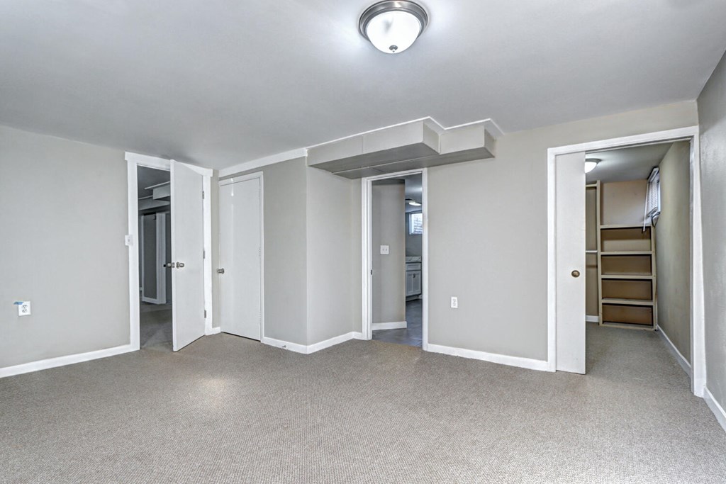 A spacious room with a carpeted floor and white walls.