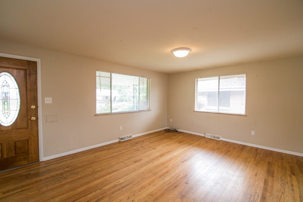 the living room of an empty house with wood floors and a door