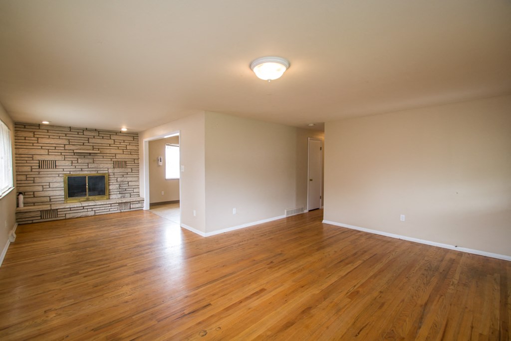 an empty living room with wood floors and a fireplace