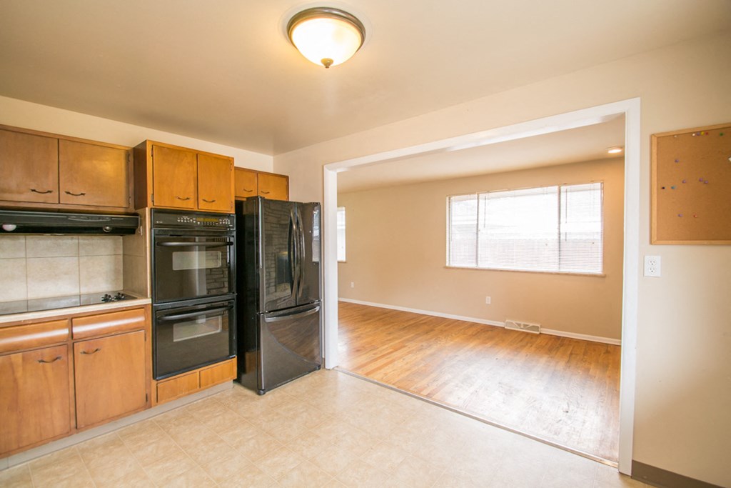 an empty kitchen with black appliances and wood floors