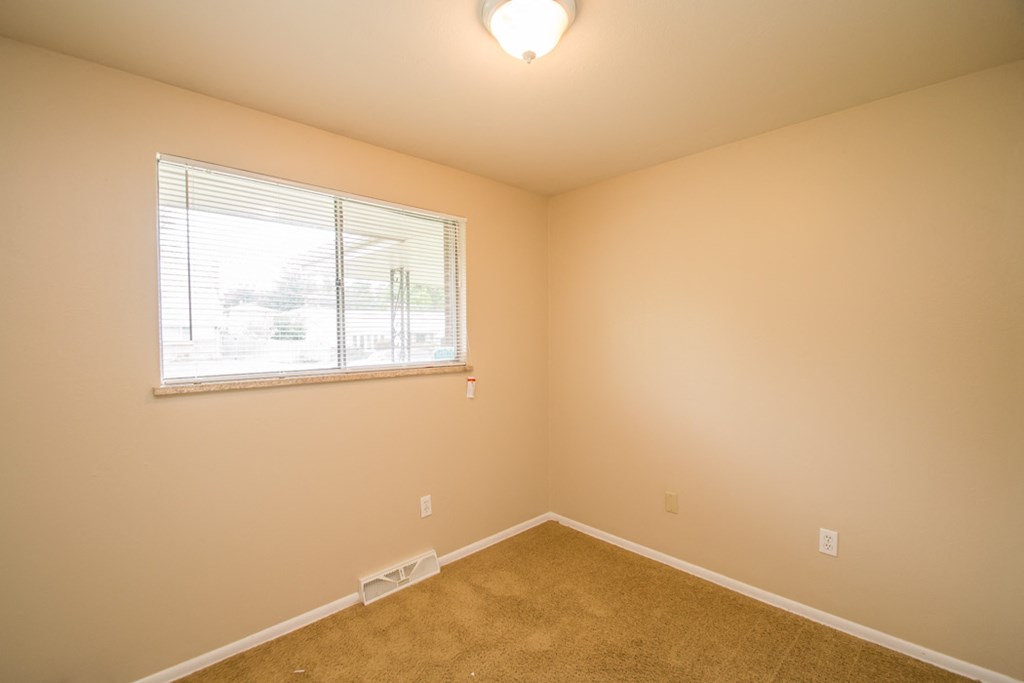 a bedroom with a window and a carpeted floor