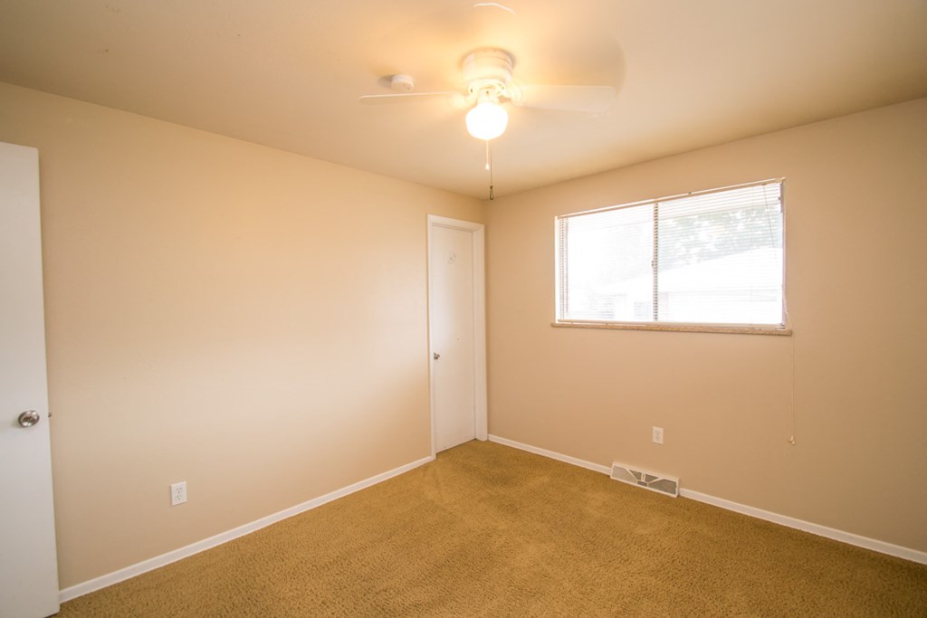 an empty living room with a window and a ceiling fan