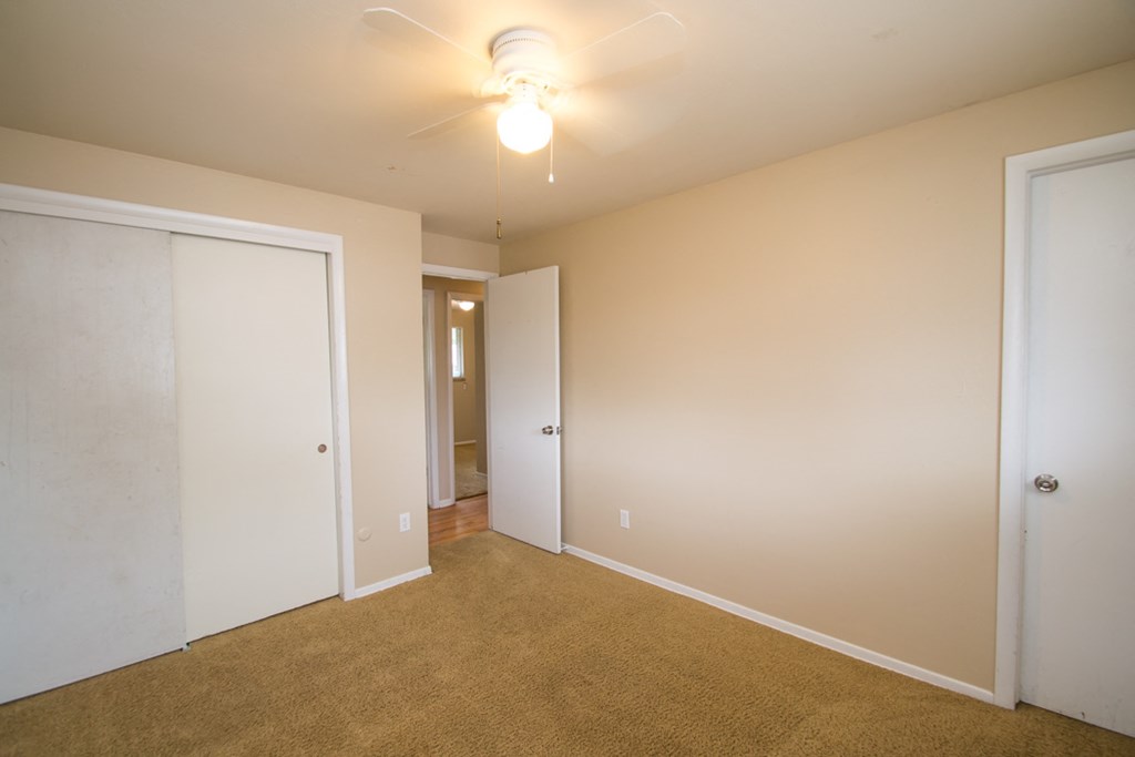 a bedroom with a carpeted floor and a ceiling fan