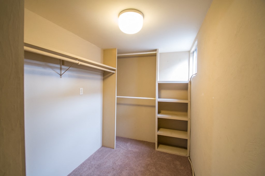 a walk in closet in a small room with shelves and a closet door