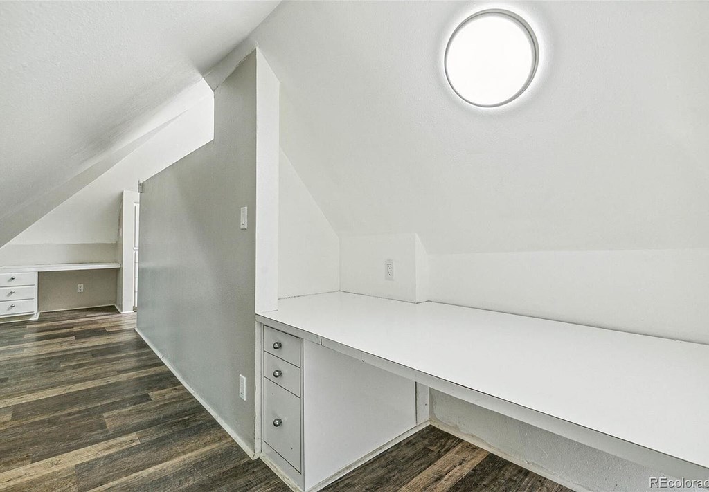 A white room with a round window and a long white bench.