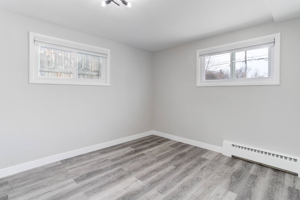 an empty room with wood flooring and two windows