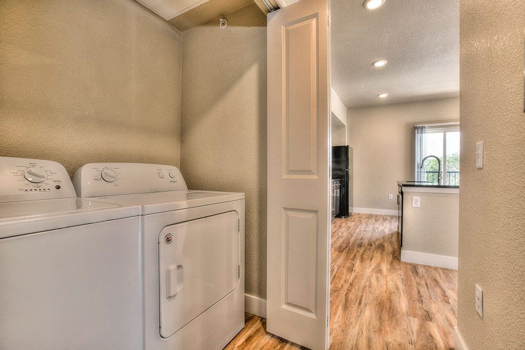 a washer and dryer in a room with a kitchen and a door open