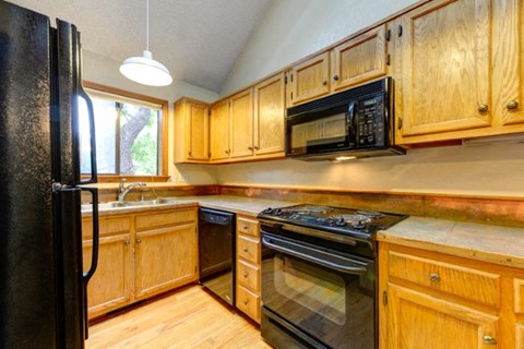 A kitchen with wooden cabinets and a black refrigerator.