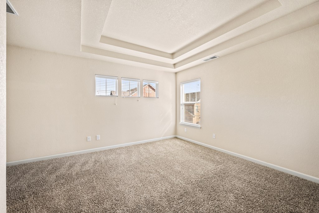 A room with carpeted floor and two windows.