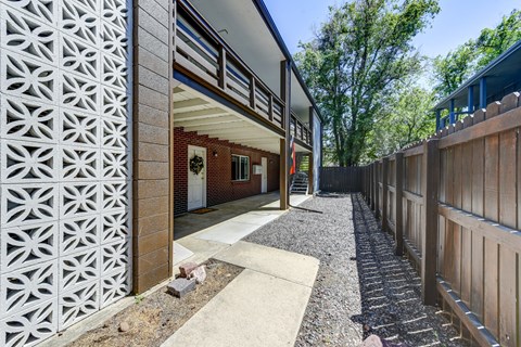 A modern house with a white and brown exterior and a gravel pathway leading to the entrance.