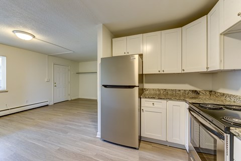 A kitchen with a stainless steel refrigerator and white cabinets.