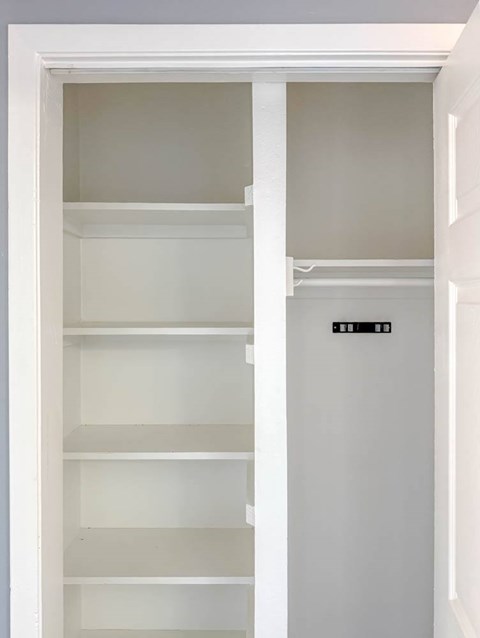 A white pantry with a white door and shelves.
