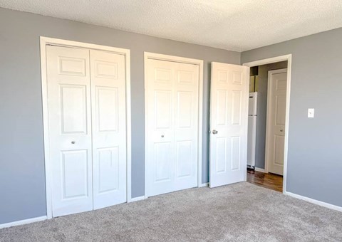 A room with three white doors and a carpeted floor.
