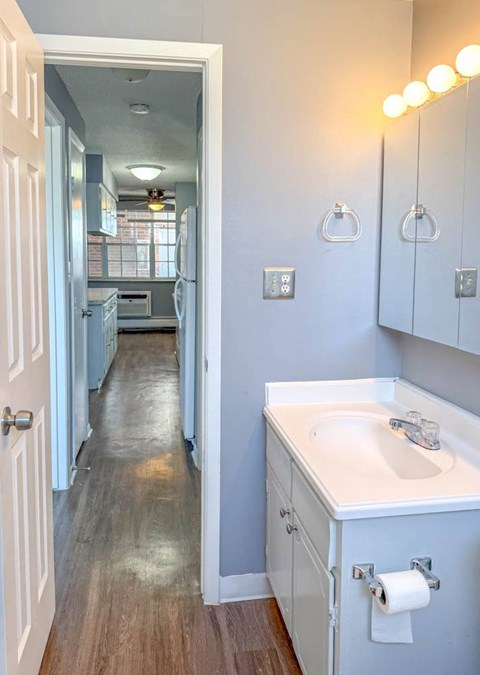 A bathroom with a sink, mirror, and light fixture.