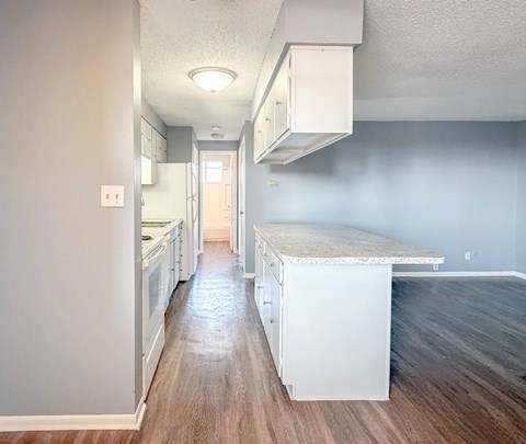 A kitchen with white cabinets and a wooden floor.