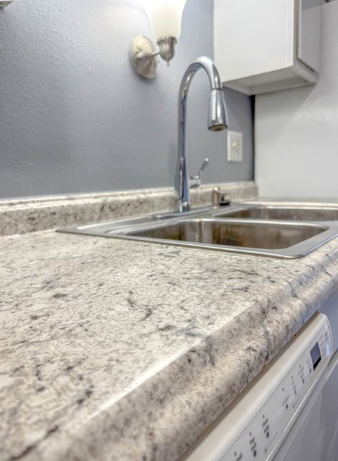 A kitchen sink with a granite counter top.