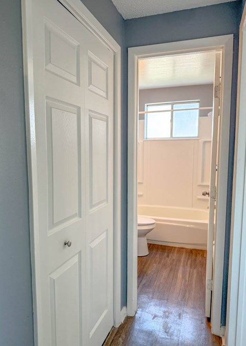 A white door is open to a bathroom with a toilet and tub.