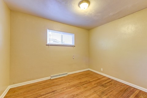 the bedroom of a home with wood flooring and a window