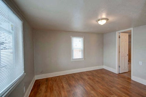 an empty living room with a wooden floor and a window