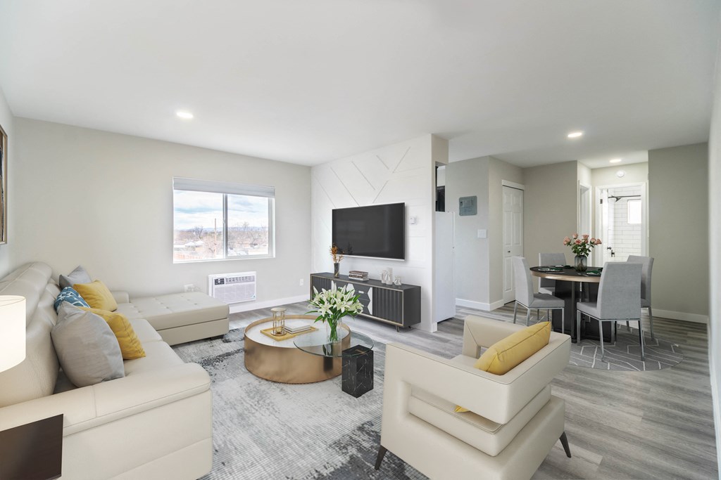 a living room with white couches and a table and a television
