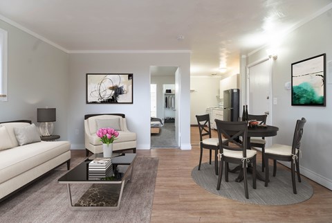 A living room with a white couch, a coffee table, and a dining table with chairs.