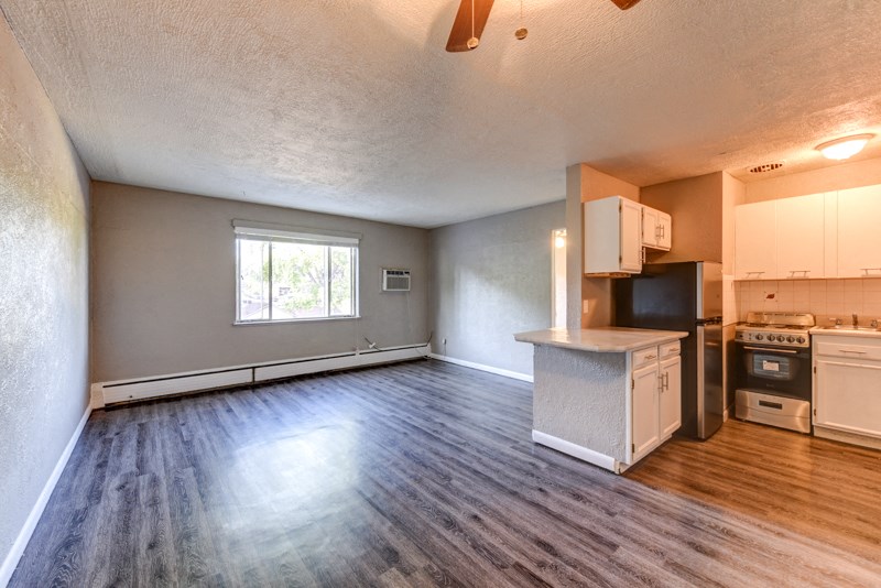 an empty living room and kitchen with a wood floor