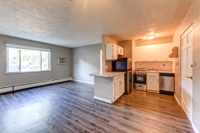 the view of a living room and kitchen with wood flooring and a window