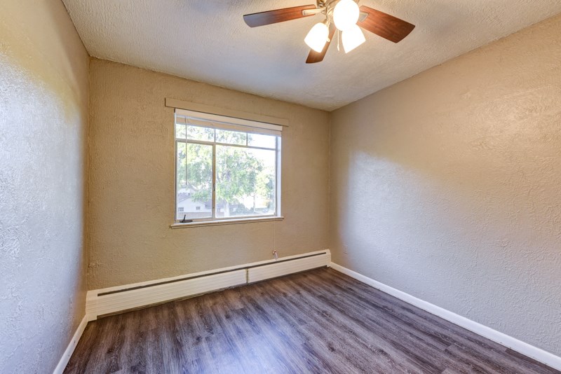 an empty living room with wood floors and a window