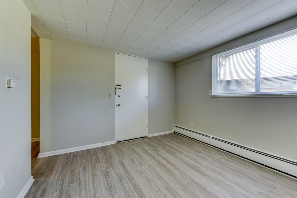 the living room of an empty apartment with wood flooring and a large window