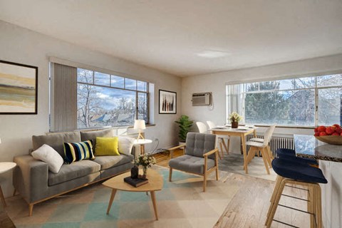 A living room with a grey couch, a wooden coffee table, and a dining table with chairs.