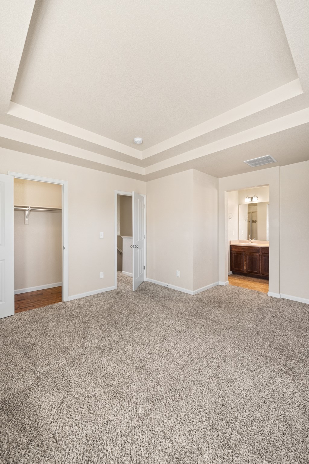 A large empty room with carpeted floor and white walls.