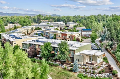 A large, modern building complex with a green landscape in the foreground.