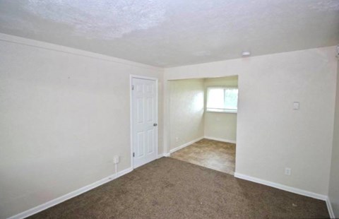 A room with a carpeted floor and a door.