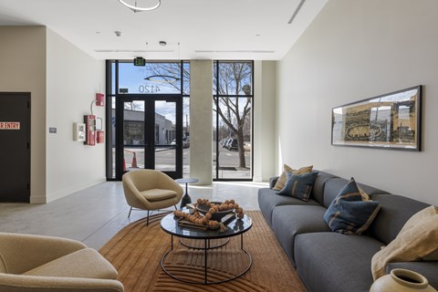 A modern living room with a grey couch, a coffee table, and a large window.