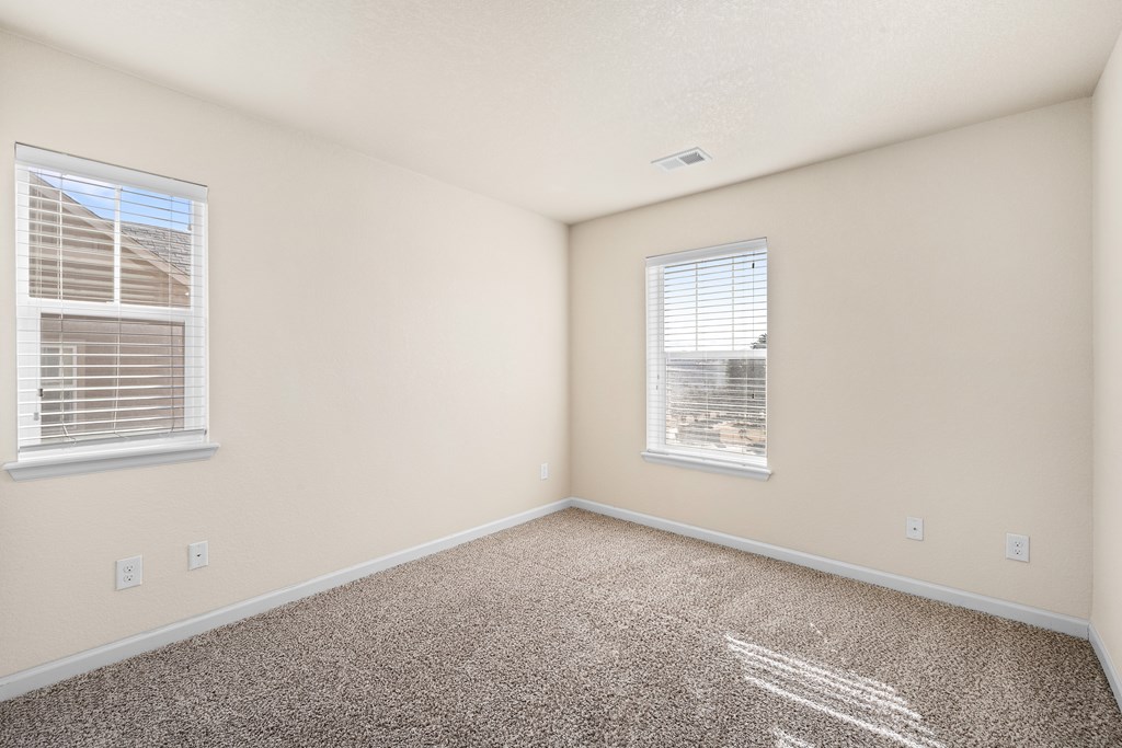 A room with two windows and carpeted floor.