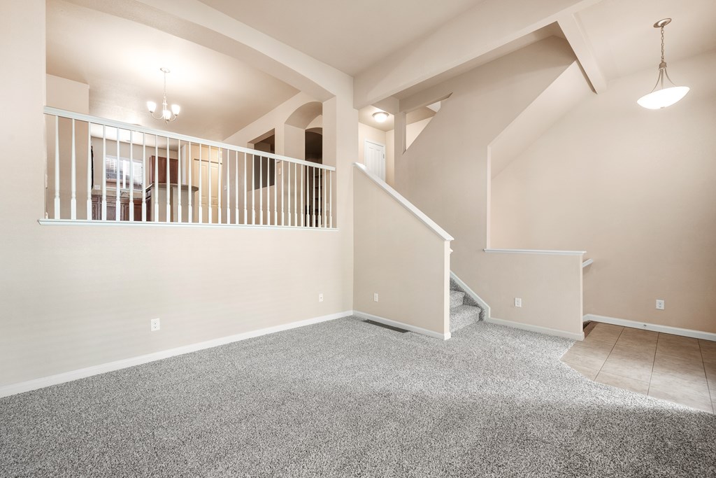 A spacious room with a carpeted floor and a staircase leading to another level.