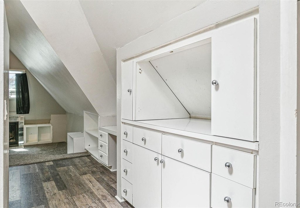 A white cabinet with drawers is in a room with a wooden floor.