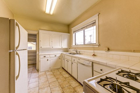 A kitchen with a refrigerator, stove, and cabinets.