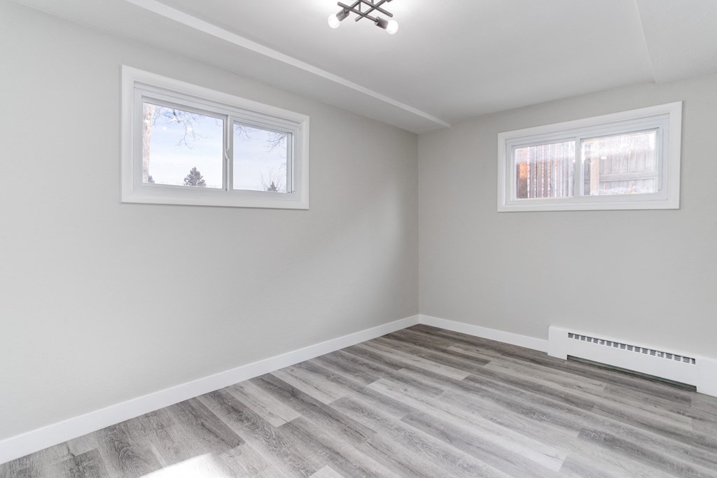 an empty room with a wood floor and two windows
