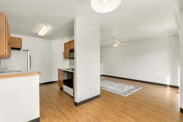 an empty living room and kitchen with wood floors