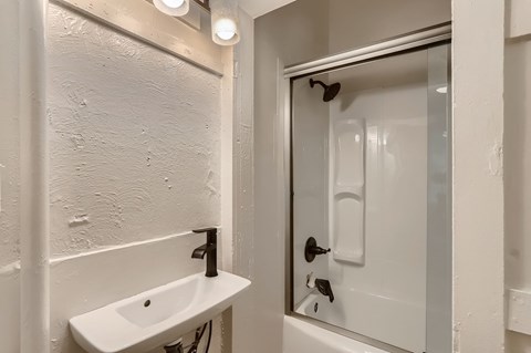 A white sink in a bathroom with a glass door shower.