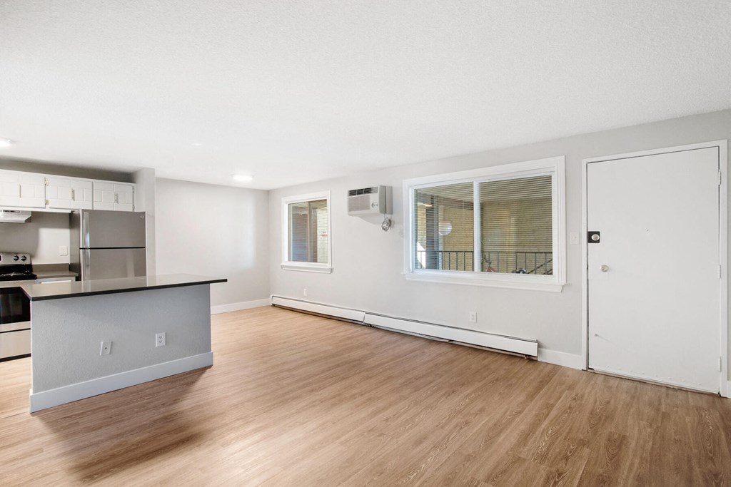 the living room and kitchen of an empty apartment with wood flooring