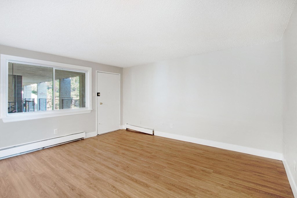 an empty living room with wood floors and a window