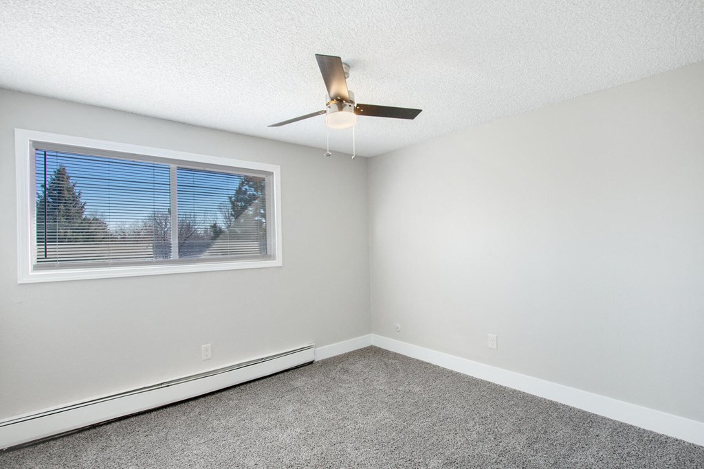 an empty room with a window and a ceiling fan