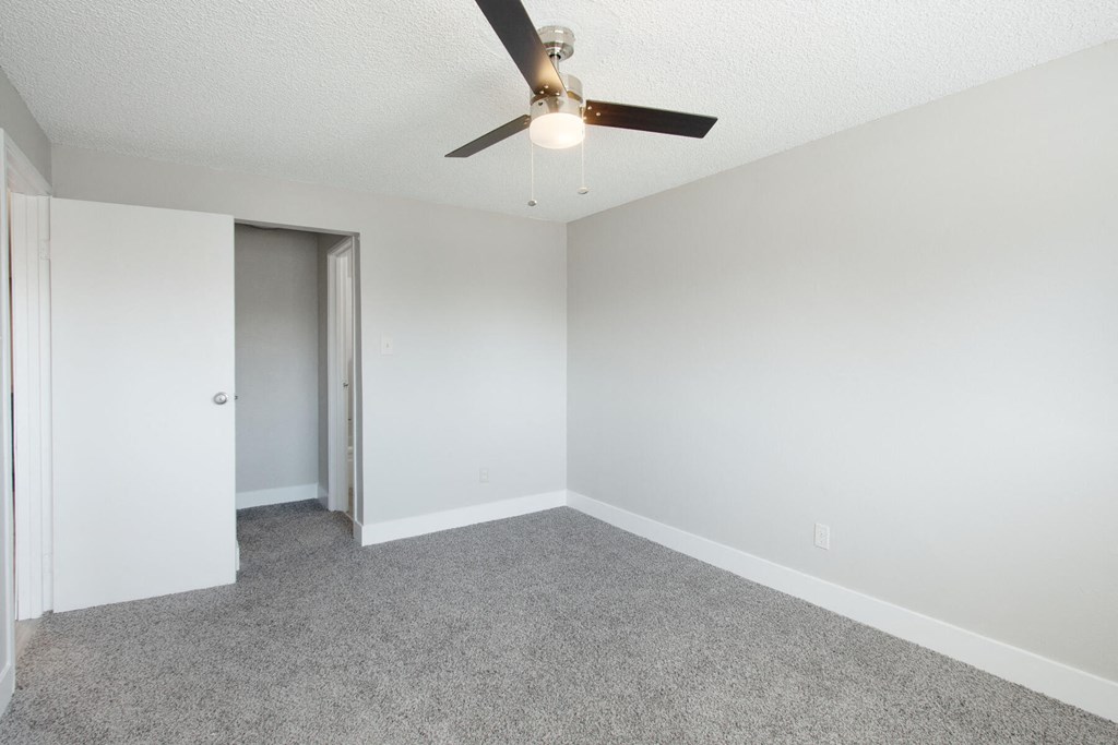 an empty room with a ceiling fan and a door to a closet